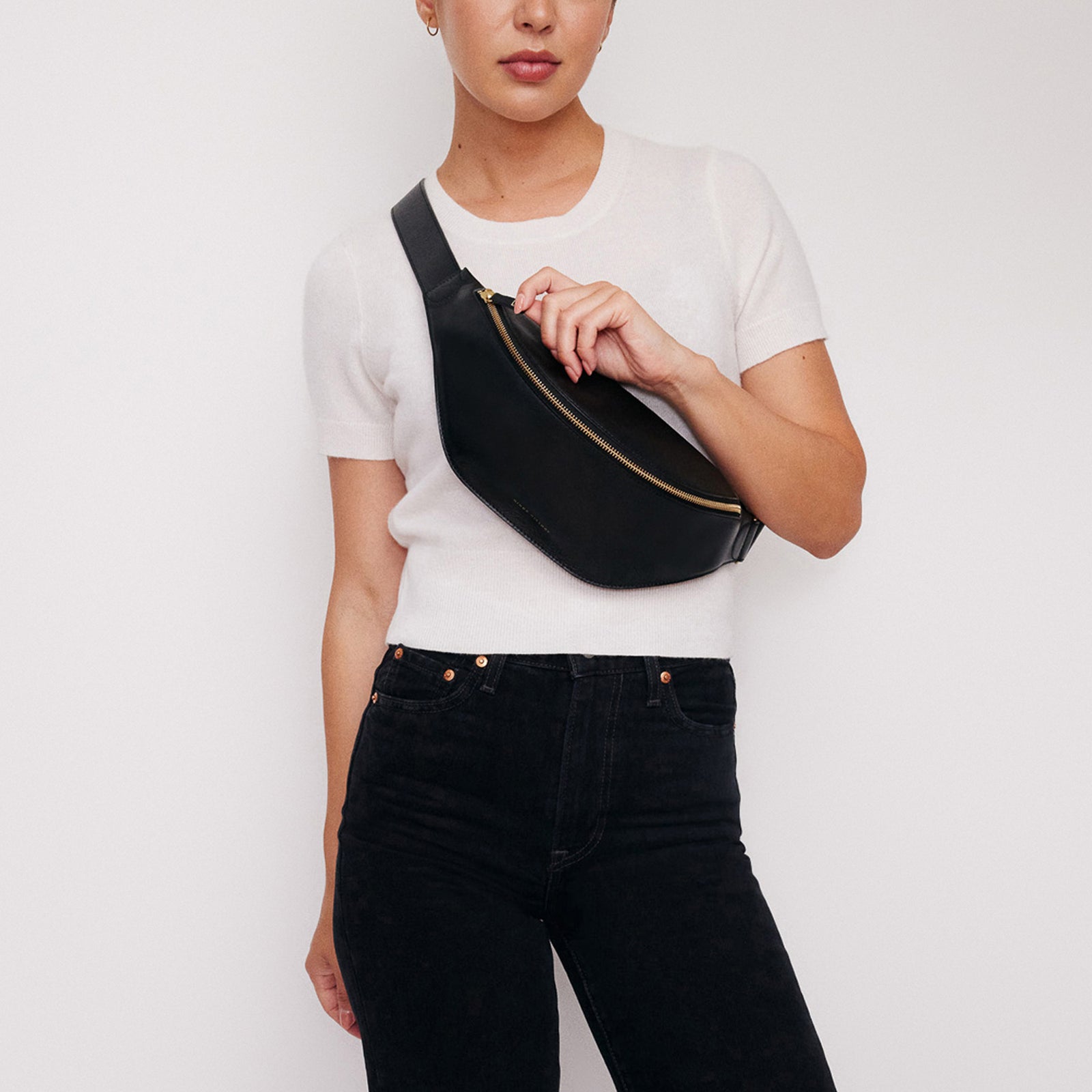 Crosstown fanny pack in black full-grain leather, cropped detail highlighting leather texture and stitching