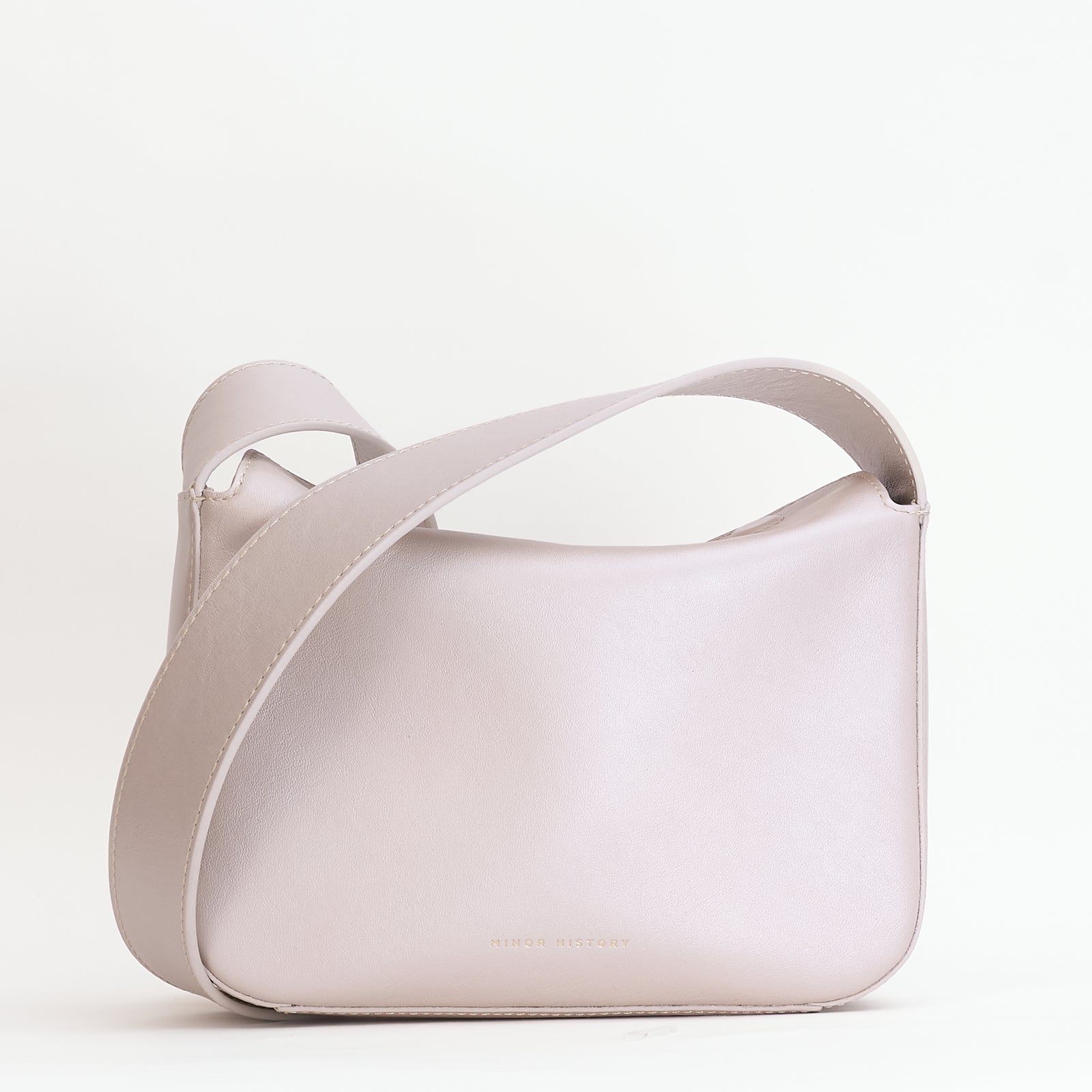 Little Frame crossbody bag in pearl full-grain leather, structured silhouette with adjustable strap against a neutral backdrop, minimalist women's handbag