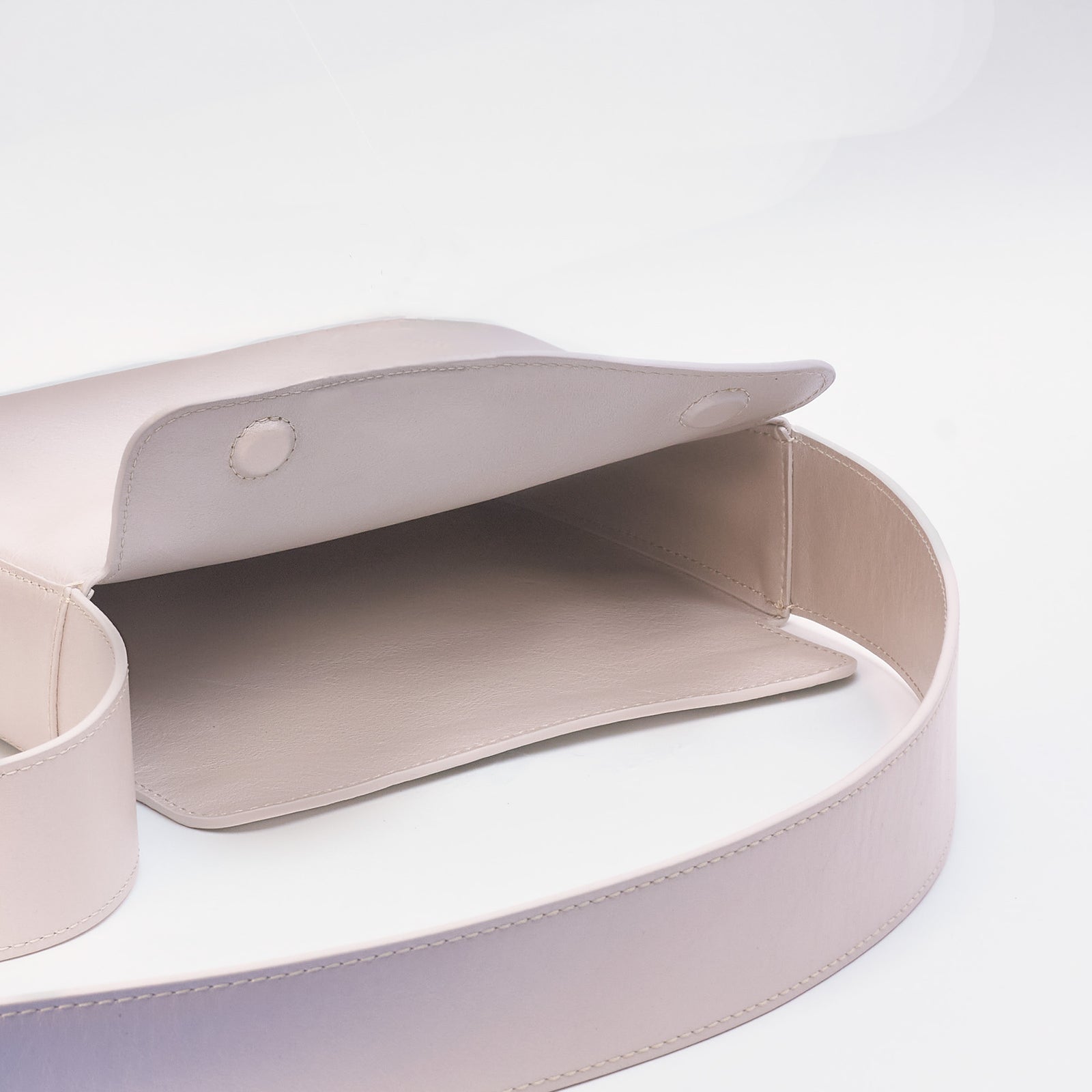 Little Frame crossbody bag in pearl full-grain leather, close-up of strap and hardware details in soft light, minimalist women's handbag