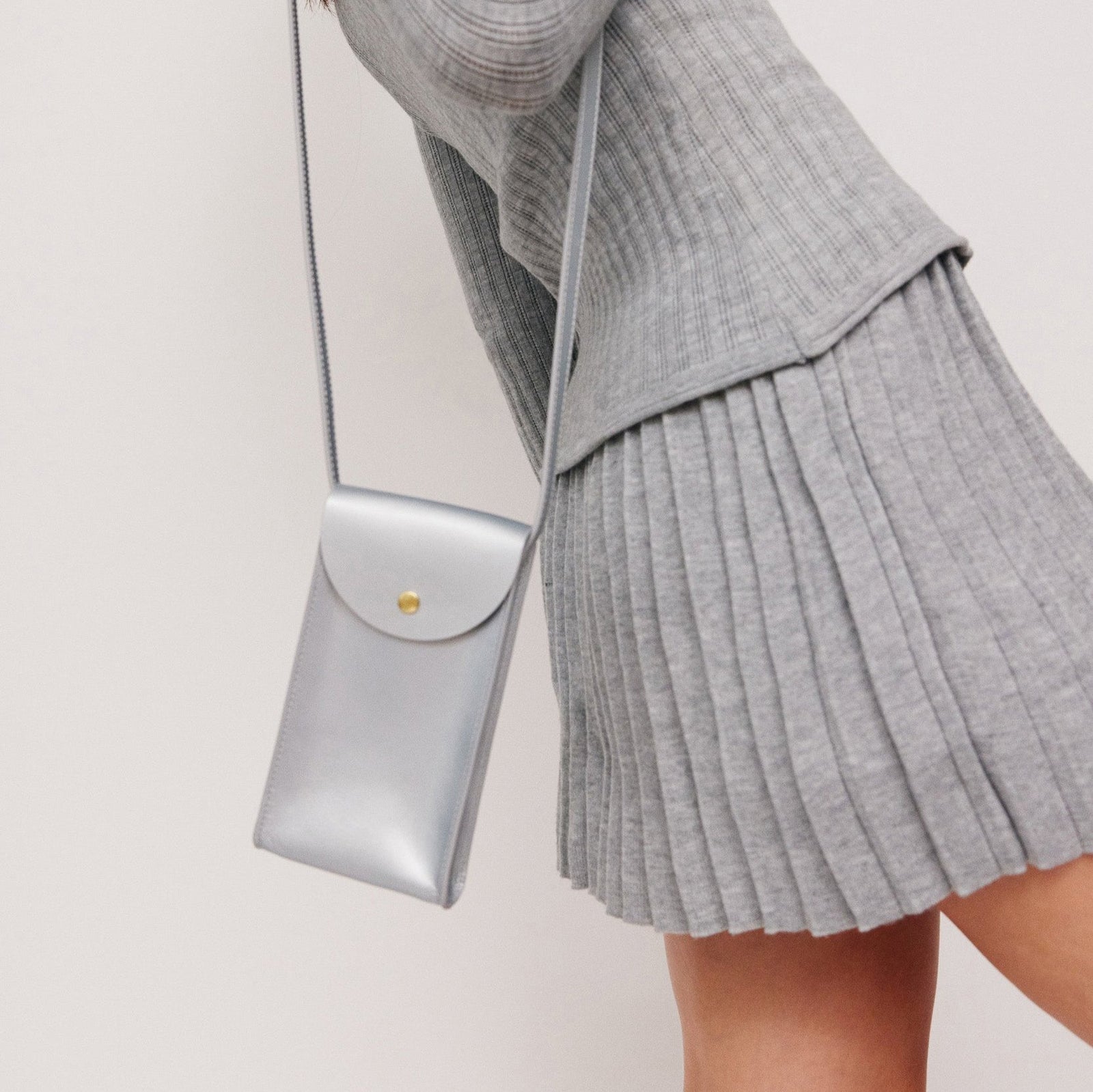 Mini Bandit crossbody bag in sterling silver full-grain leather, angled side view showing strap and shape