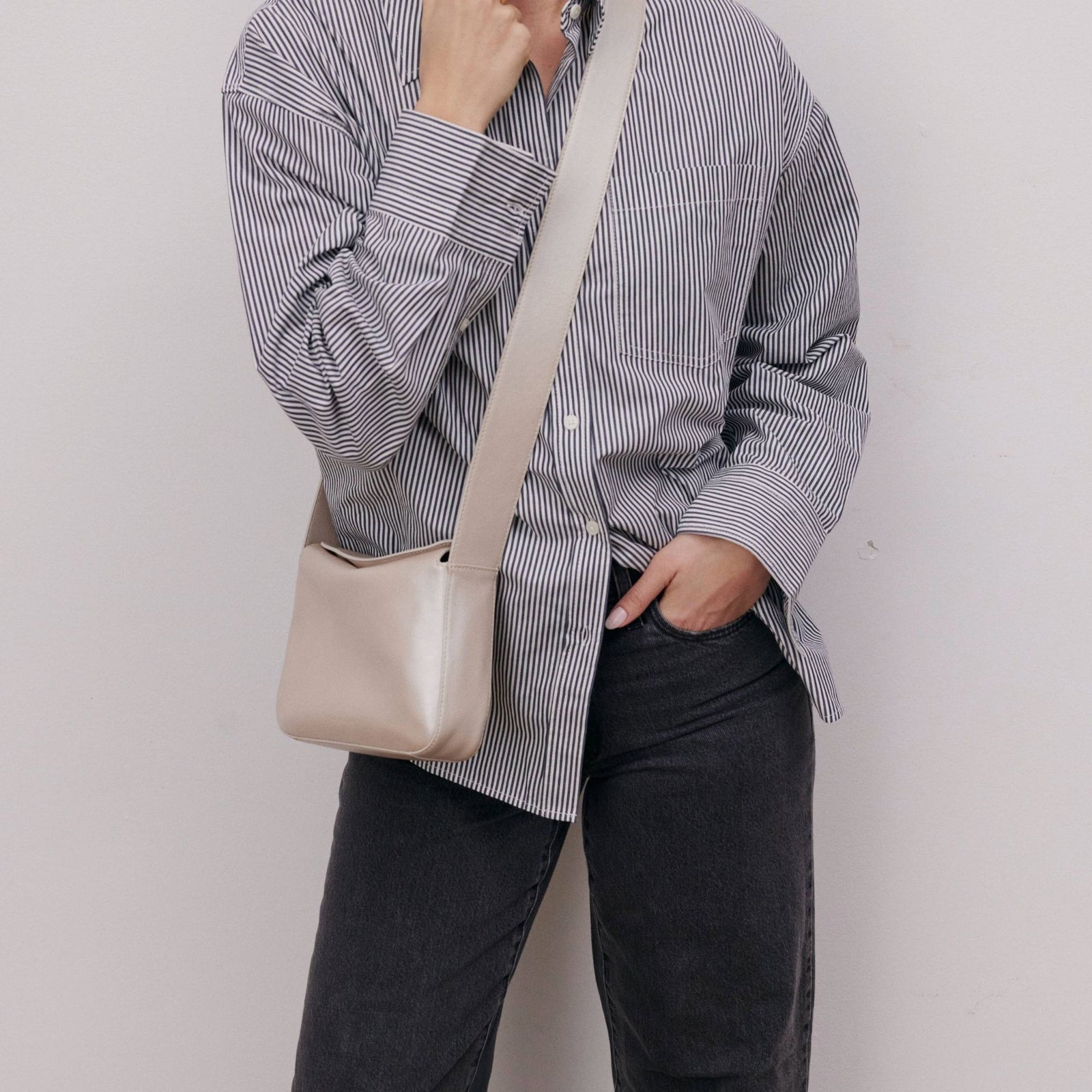 White Metallic Leather Crossbody on model wearing a striped shirt and black jeans.
