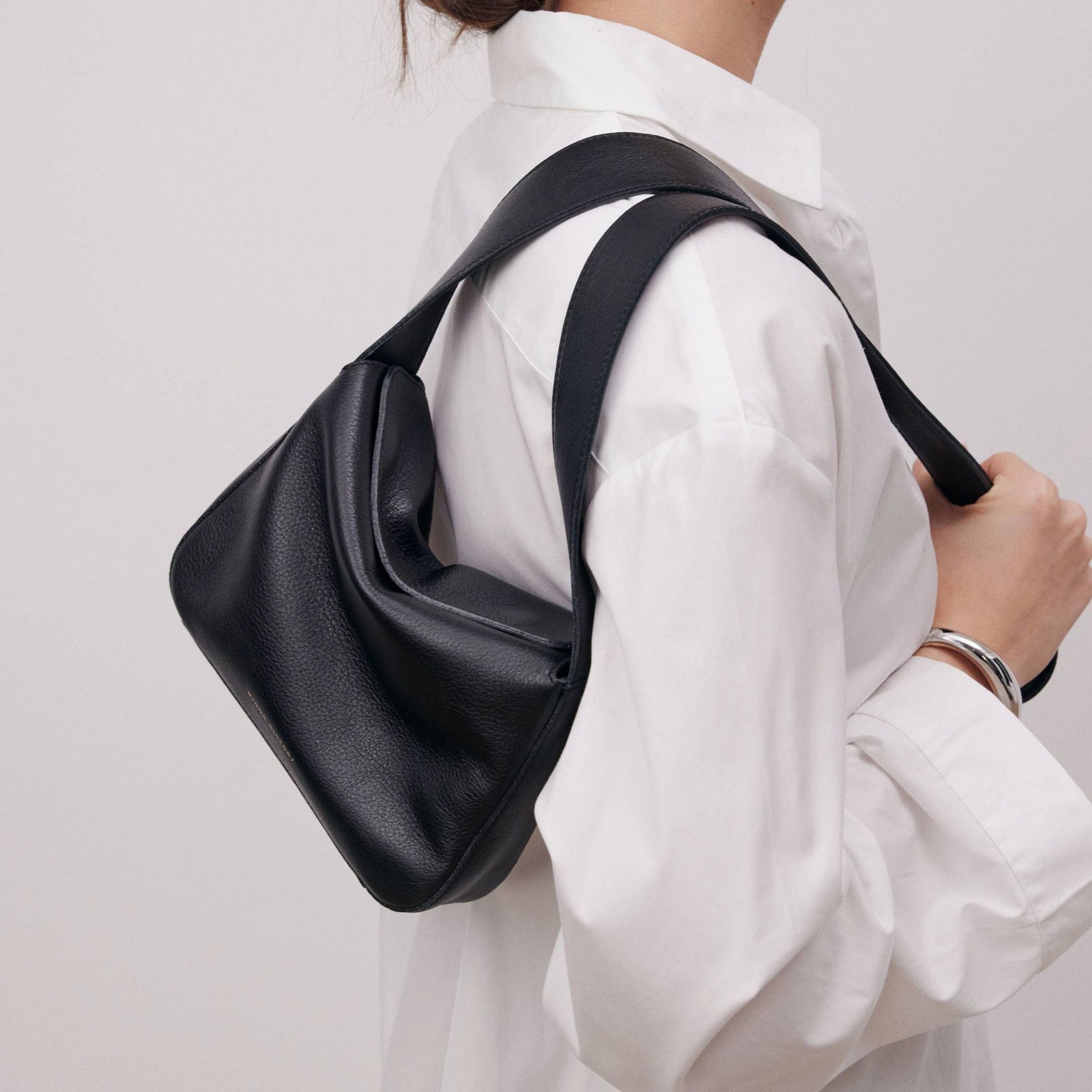 Little Frame crossbody bag in black full-grain leather styled with neutral-toned outfit for a fresh, everyday look, minimalist women's handbag