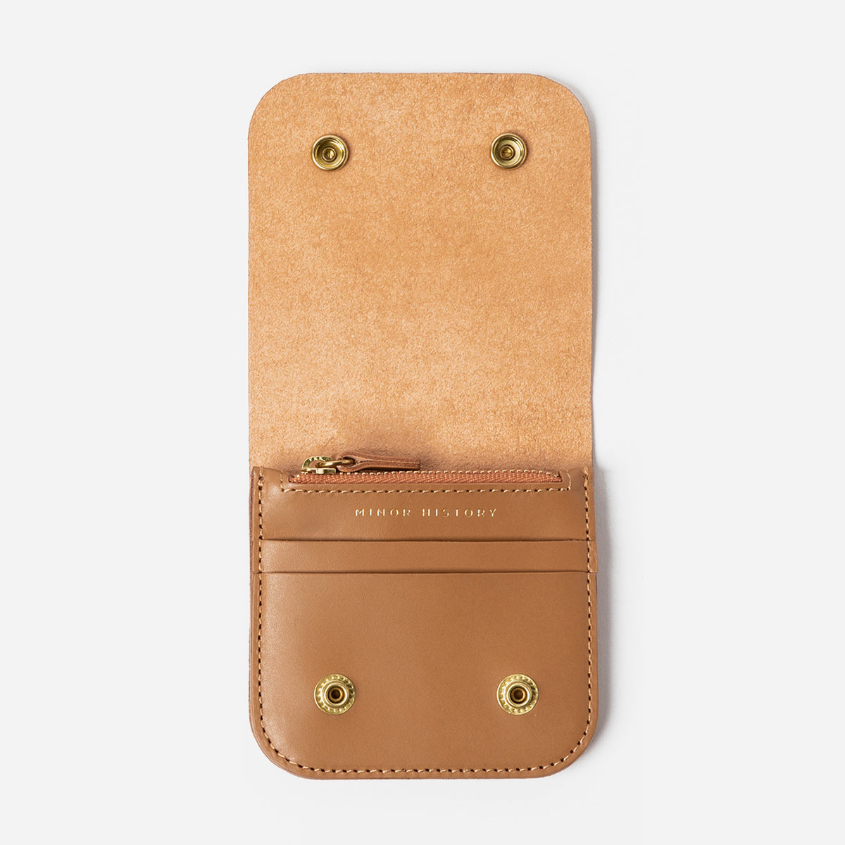 Tan leather wallet with gold accents on a light gray background - Saddle
