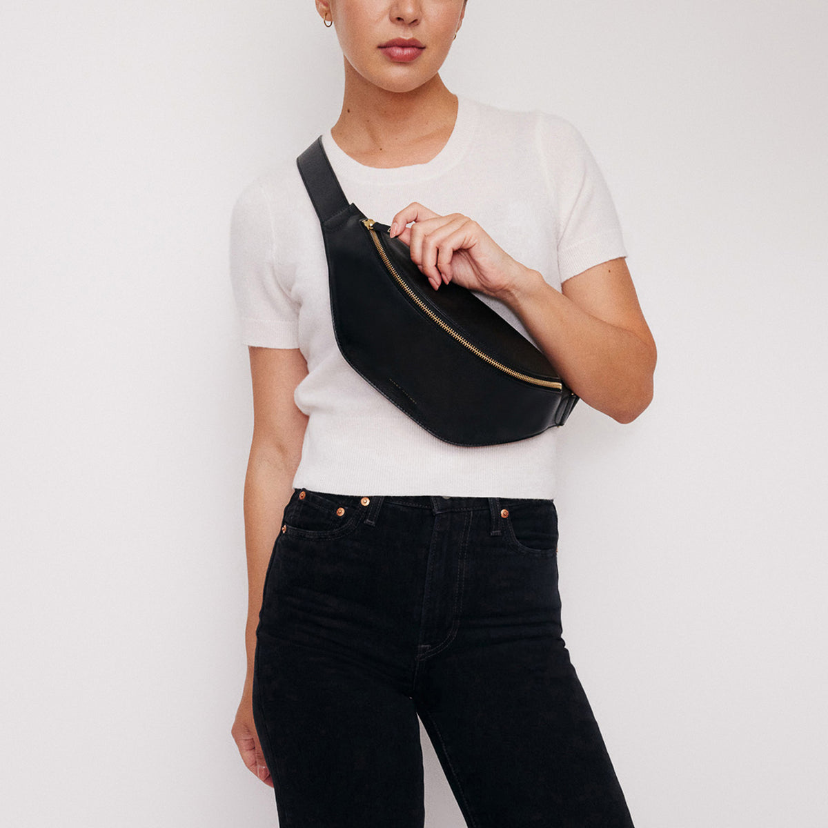 Crosstown fanny pack in black full-grain leather, cropped detail highlighting leather texture and stitching