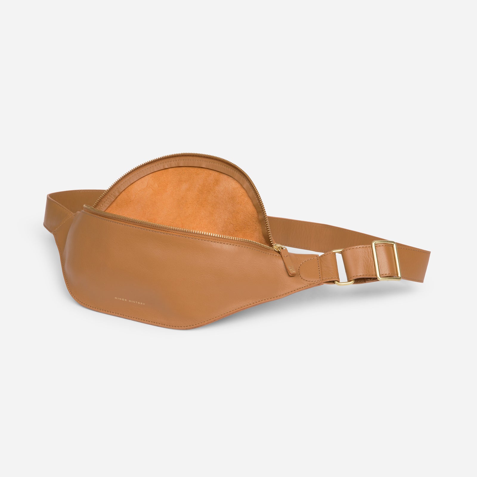 Crosstown fanny pack in saddle brown full-grain leather, angled side view showing strap design