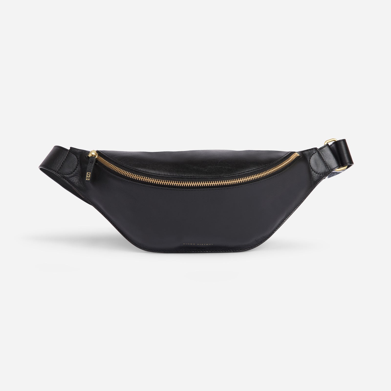 Crosstown sling bag in black full-grain leather, angled side view showing strap design