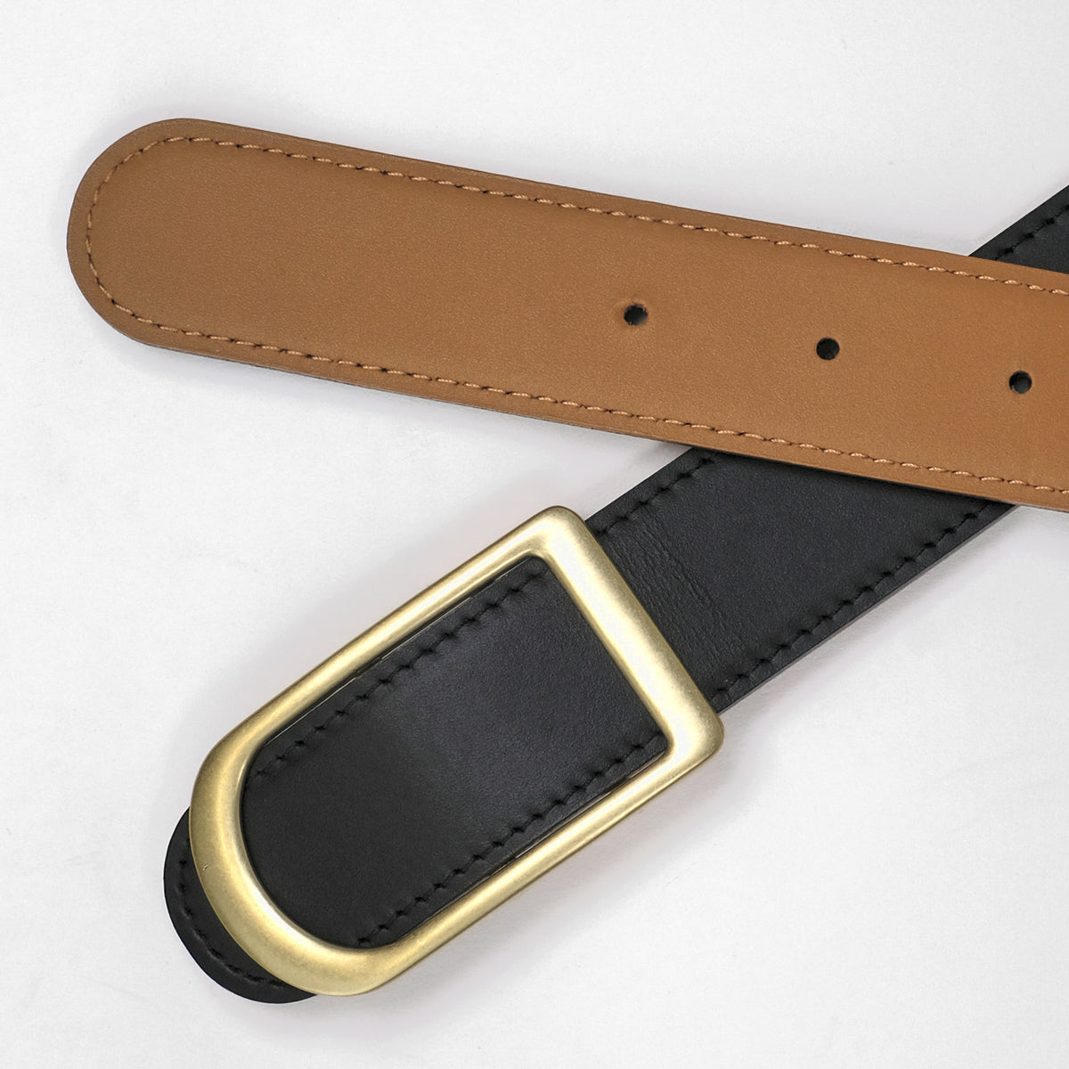 Gemini reversible belt in black and saddle brown full-grain leather with brass buckle, displayed in bright studio with soft shadows