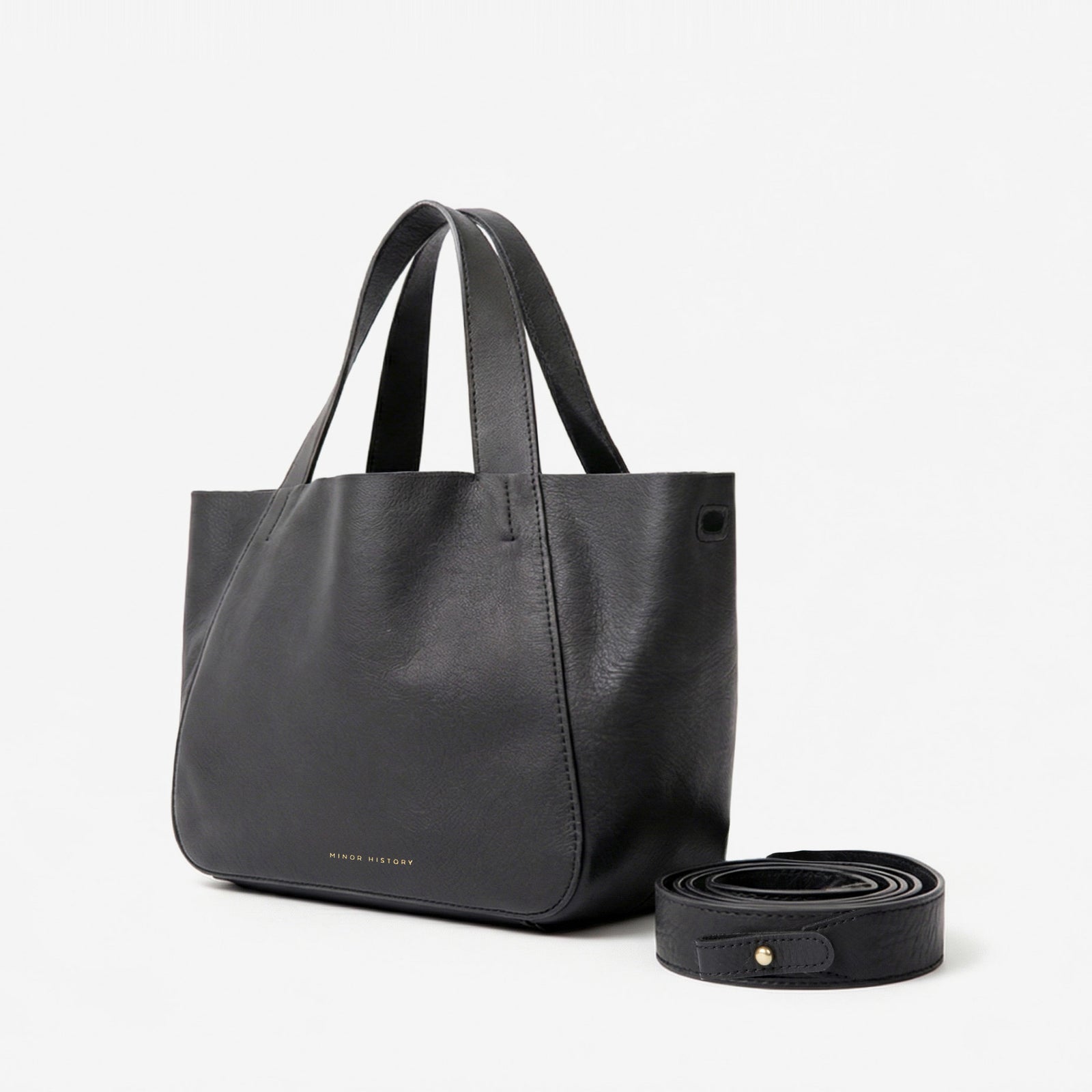 Black leather tote bag with matching strap on a light gray background  - Black