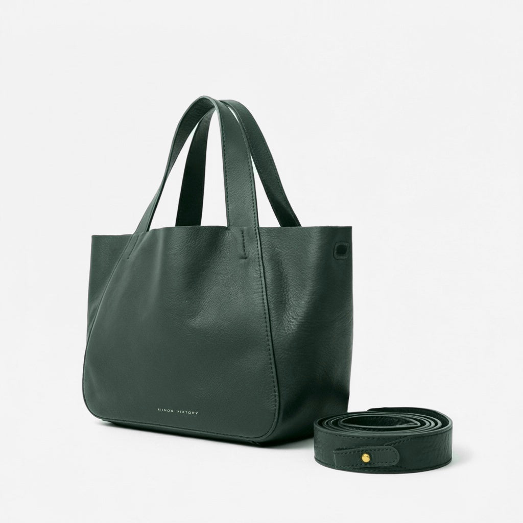 Green leather tote bag with matching strap on a light gray background - Evergreen