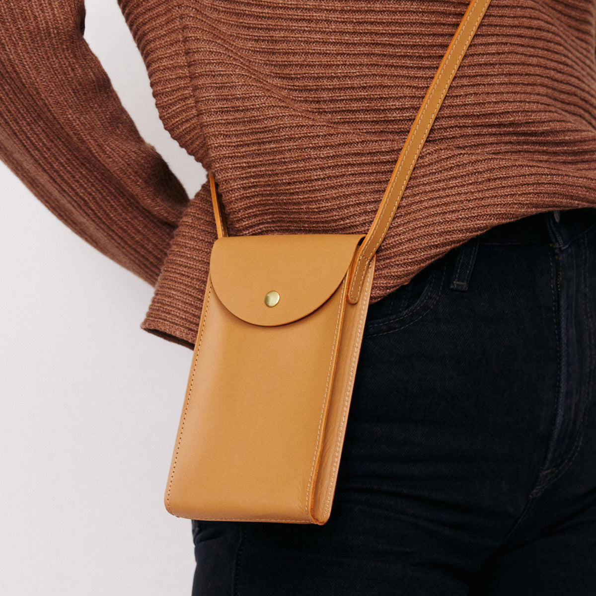 Mini Bandit crossbody bag in saddle brown full-grain leather, cropped view highlighting texture and stitching