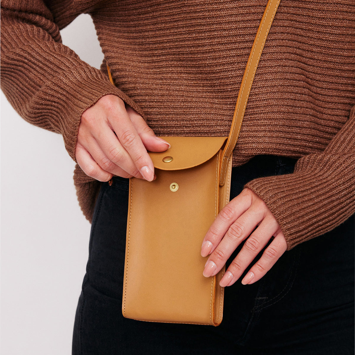 Mini Bandit crossbody bag in saddle brown full-grain leather, cropped view highlighting texture and stitching