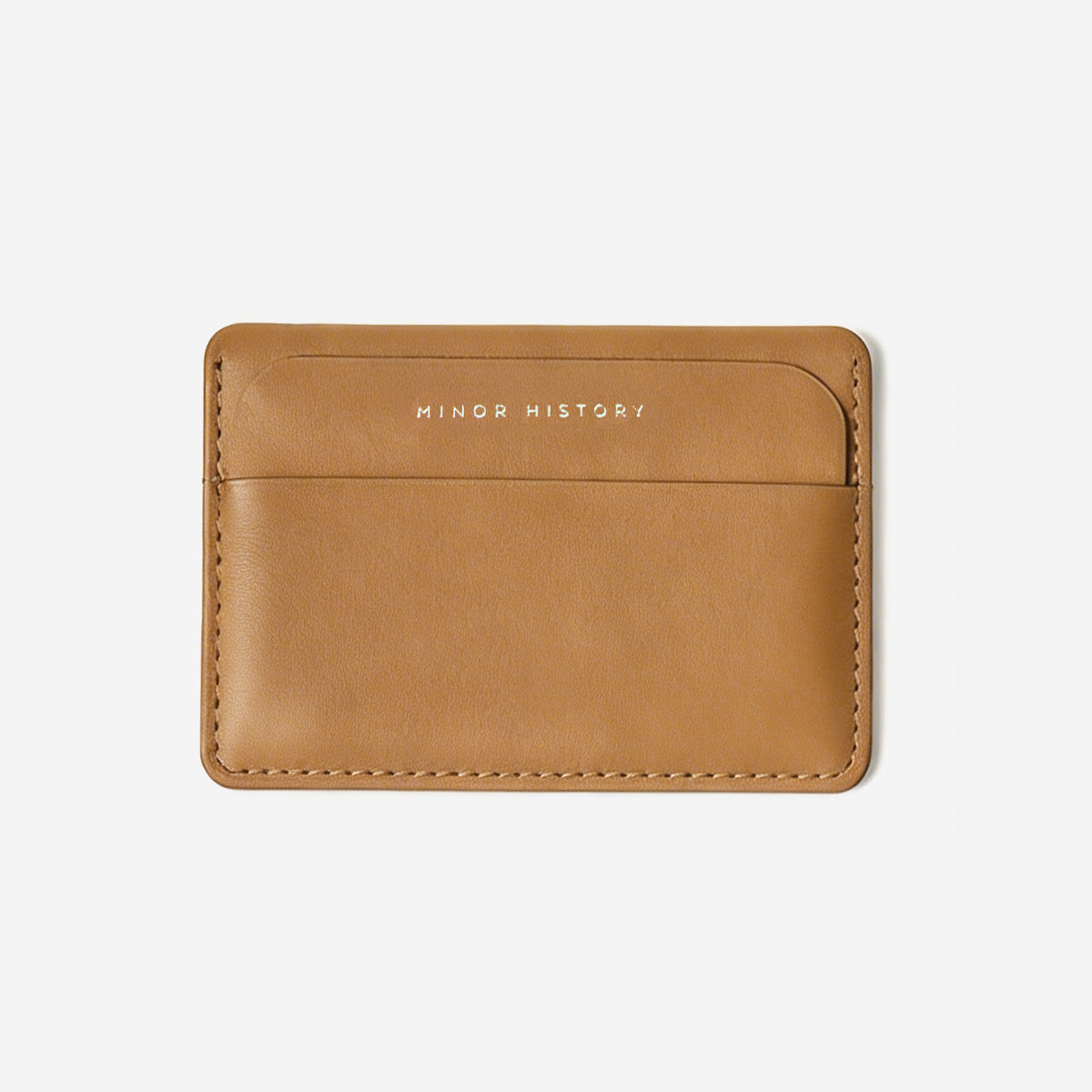 Brown leather cardholder with 'MINOR HISTORY' branding on a light gray background - Saddle

