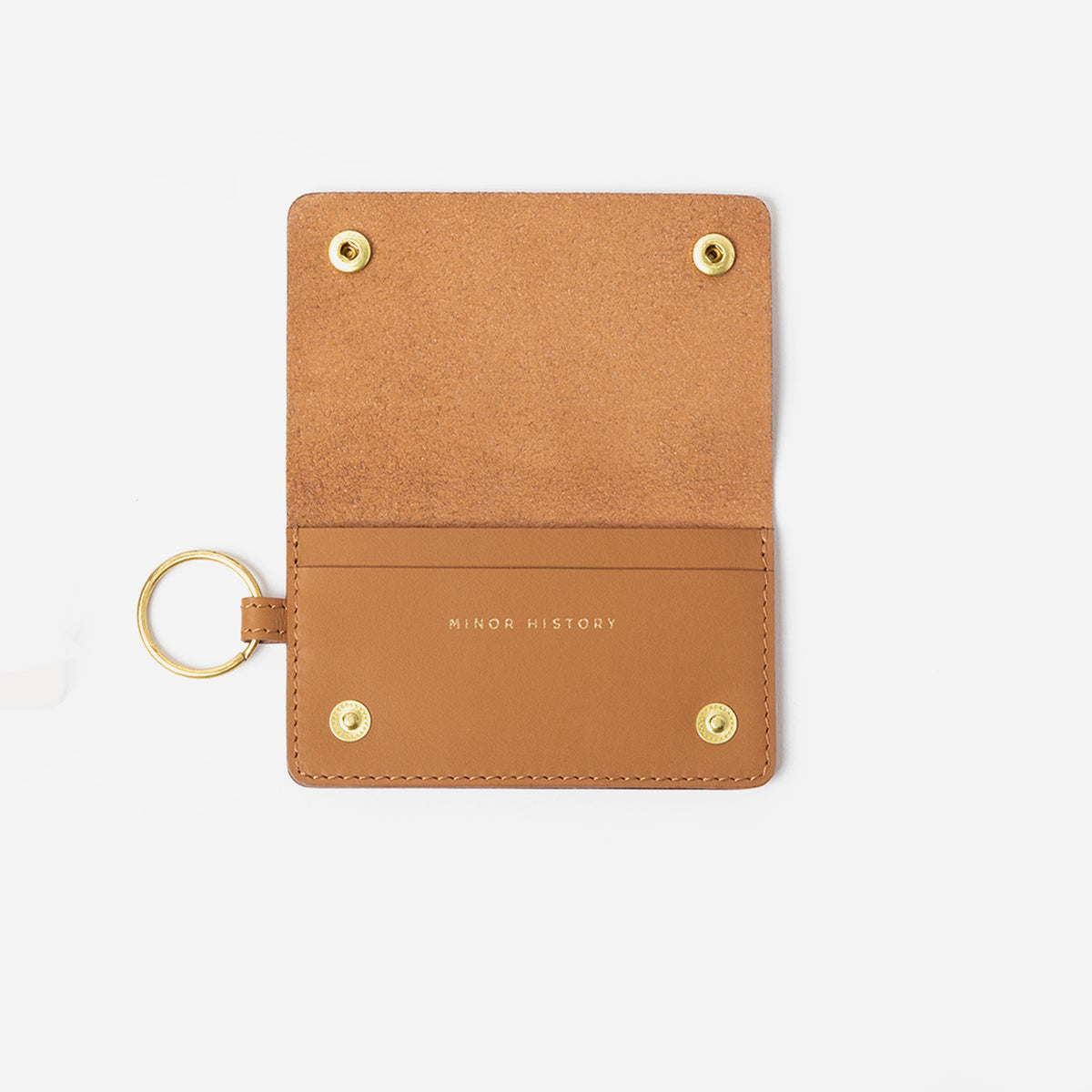 Tan leather cardholder with gold accents on a white background - Saddle