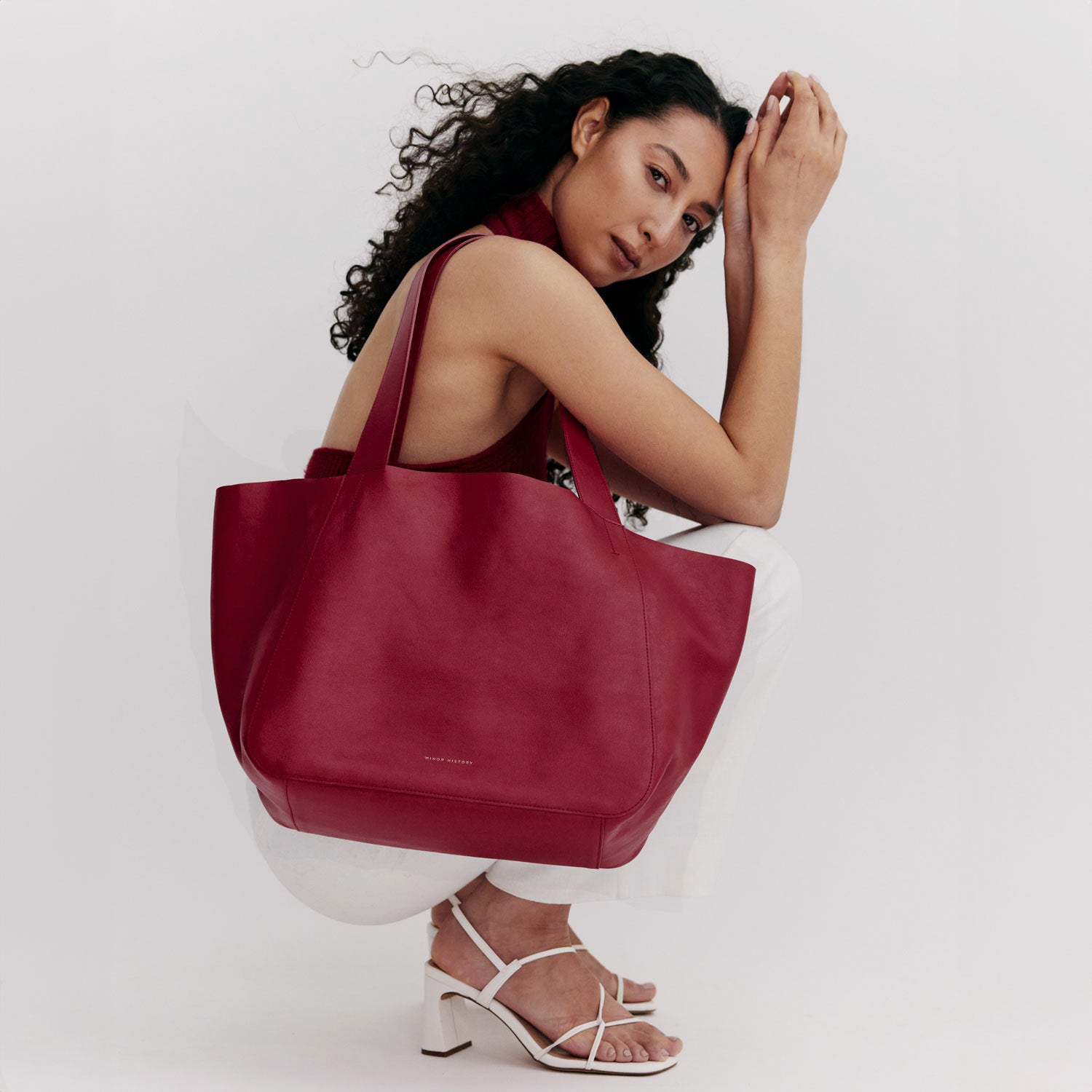 Woman holding a red handbag against a white background -cherry cola