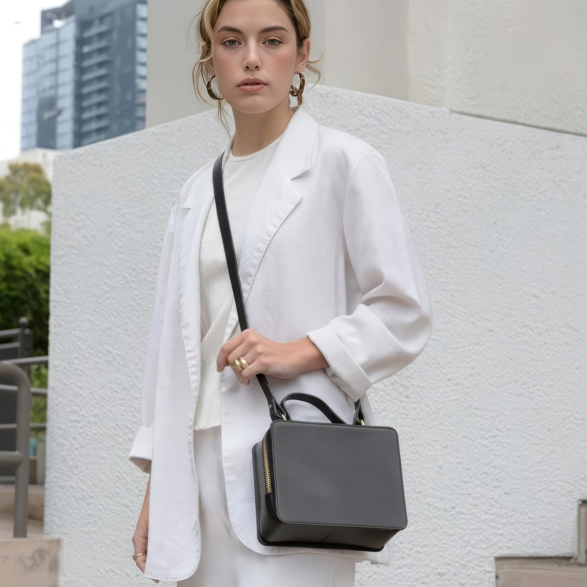 Black handbag with gold zipper on a light gray background - Black